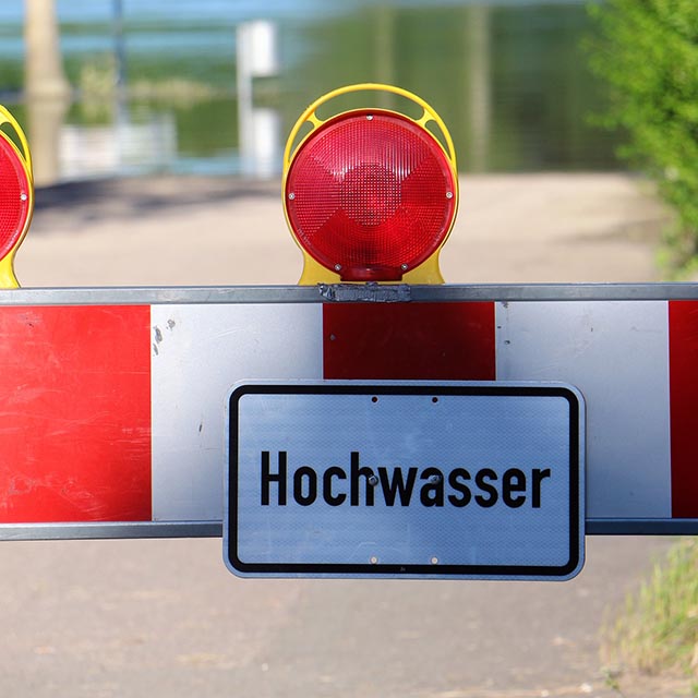 Dieses Bild zeigt eine Absperrbake mit der Aufschrift "Hochwasser". Bild von Sandhaase auf Pixabay