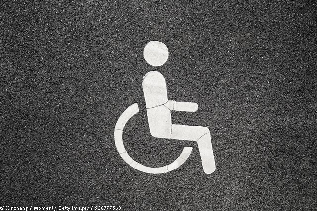 Dieses Bild zeigt ein auf Asphalt aufgemaltes Piktogramm eines Rollstuhls. © Xinzheng / Moment / Getty Images / 930777568