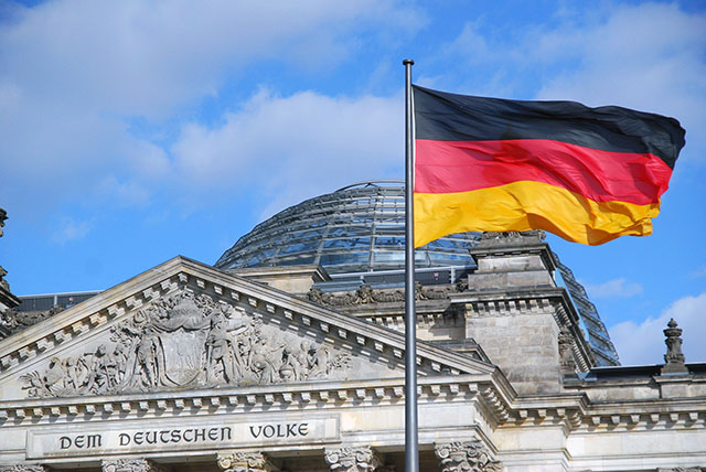 Dieses Bild zeigt die Bundesflagge vor dem Reichstagsgebäude. Bild von Jörn Heller auf Pixabay